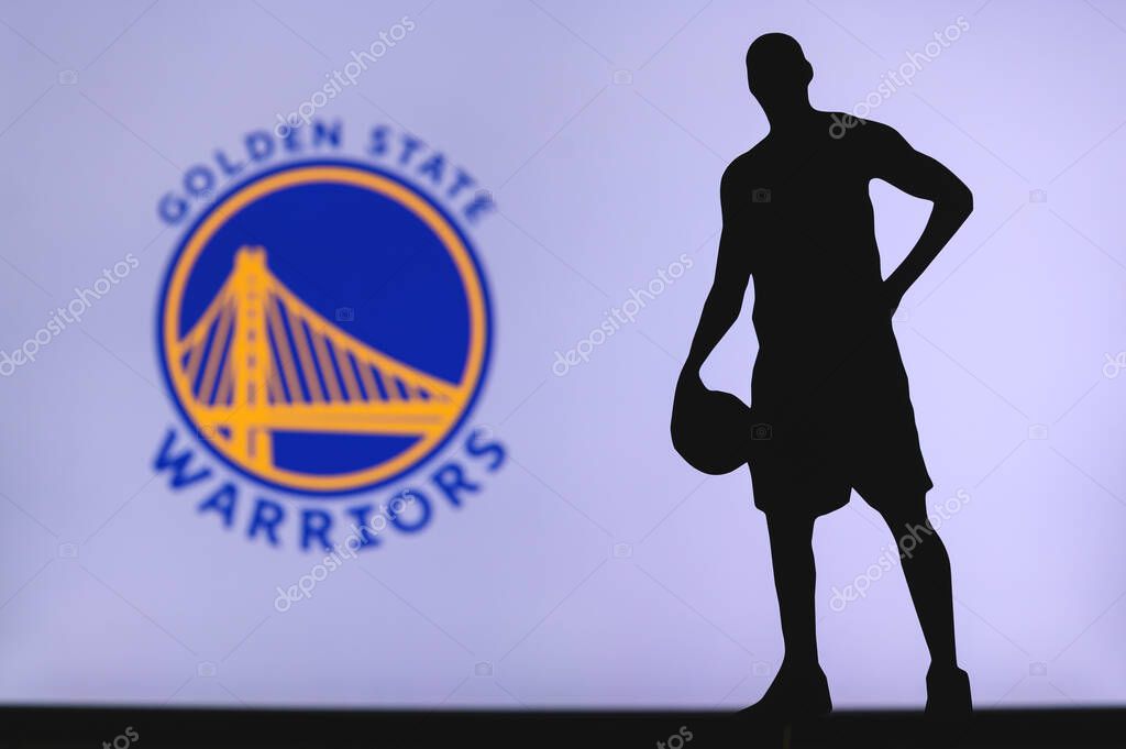 NEW YORK, USA, JUN 18, 2020: Golden State Warriors logo of professional basketball club in american league. Silhouette of basket player in foreground. Sport concept photo, edit space.