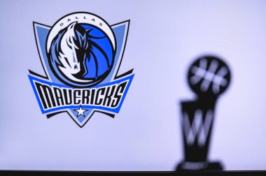 NEW YORK, USA, JUN 18, 2020: Dallas Mavericks Basketball club on the white screen. Silhouette of NBA trophy in foreground. clipart