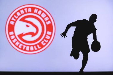 NEW YORK, ABD, 18 Haziran 2020: Atlanta Hawks basketbol kulübü logosu ve genç basketbolcunun silüeti. Spor duvar kağıdı, arkaplanda beyaz düzenleme alanı.