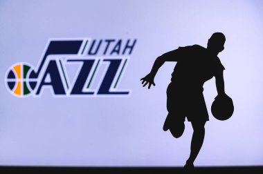 NEW YORK, ABD, 18 Haziran 2020: Utah Jazz basketbol kulübü logosu ve genç basketbolcunun silüeti. Spor duvar kağıdı, arkaplanda beyaz düzenleme alanı.