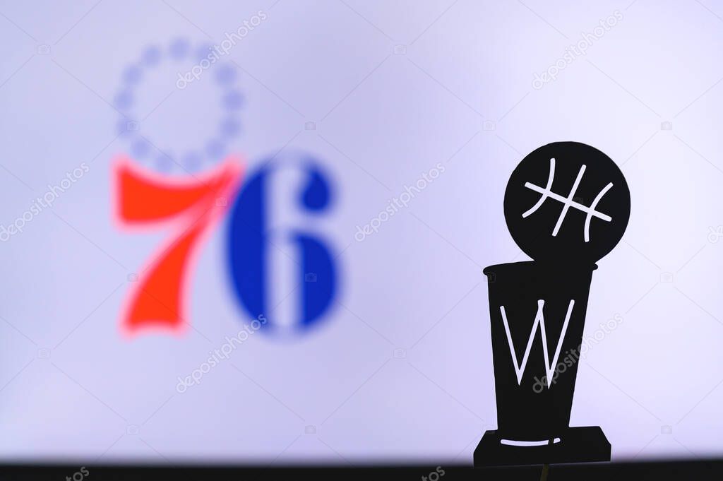 NEW YORK, USA, JUN 18, 2020: Philadelphia 76ers Basketball club on the white screen. Silhouette of NBA trophy in foreground.