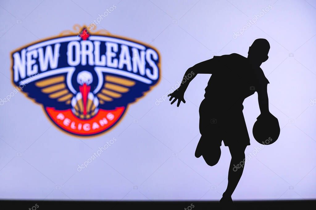NEW YORK, USA, JUN 18, 2020: New Orleans Pelicans basketball club logo and silhouette of young basketball player. Sport wallpaper, white edit space in background.