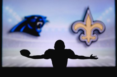 Carolina Panthers, New Orleans Saints 'e karşı. NFL oyunu. Amerikan Futbol Ligi maçı. Profesyonel oyuncunun silueti dokunuşu kutluyor. Arkaplanda ekran.