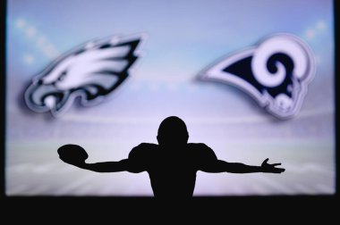 Philadelphia Eagles Los Angeles Rams 'a karşı. NFL oyunu. Amerikan Futbol Ligi maçı. Profesyonel oyuncunun silueti dokunuşu kutluyor. Arkaplanda ekran.