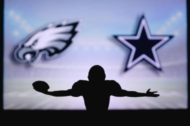 Philadelphia Eagles Dallas Cowboys 'a karşı. NFL oyunu. Amerikan Futbol Ligi maçı. Profesyonel oyuncunun silueti dokunuşu kutluyor. Arkaplanda ekran.