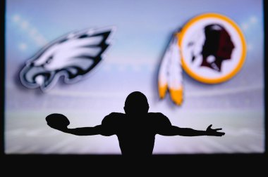 Philadelphia Eagles, Washington Redskins 'e karşı. NFL oyunu. Amerikan Futbol Ligi maçı. Profesyonel oyuncunun silueti dokunuşu kutluyor. Arkaplanda ekran.