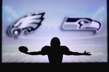 Philadelphia Eagles, Seattle Seahawks 'a karşı NFL maçı. Amerikan Futbol Ligi maçı. Profesyonel oyuncunun silueti dokunuşu kutluyor. Arkaplanda ekran.