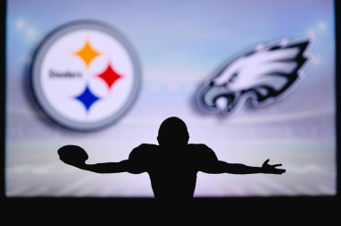 Pittsburgh Steelers, Philadelphia Eagles 'a karşı. NFL oyunu. Amerikan Futbol Ligi maçı. Profesyonel oyuncunun silueti dokunuşu kutluyor. Arkaplanda ekran.