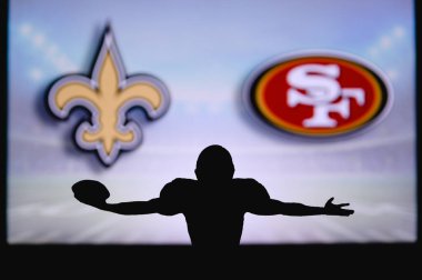 New Orleans Saints, San Francisco 49ers 'a karşı. NFL oyunu. Amerikan Futbol Ligi maçı. Profesyonel oyuncunun silueti dokunuşu kutluyor. Arkaplanda ekran.