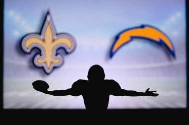 New Orleans Saints Los Angeles Chargers 'a karşı. NFL oyunu. Amerikan Futbol Ligi maçı. Profesyonel oyuncunun silueti dokunuşu kutluyor. Arkaplanda ekran.