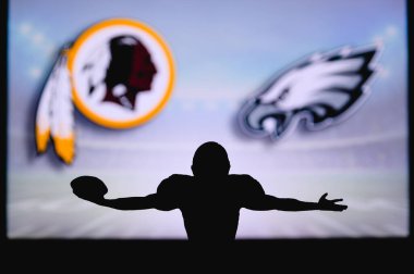 Washington Redskins Philadelphia Eagles 'a karşı. NFL oyunu. Amerikan Futbol Ligi maçı. Profesyonel oyuncunun silueti dokunuşu kutluyor. Arkaplanda ekran.
