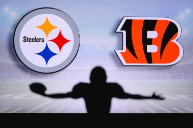 Pittsburgh Steelers, Cincinnati Bengalleri 'ne karşı. NFL oyunu. Amerikan Futbol Ligi maçı. Profesyonel oyuncunun silueti dokunuşu kutluyor. Arkaplanda ekran.