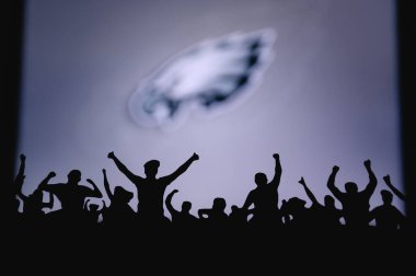 Philadelphia Kartalları. Taraftarlar Amerikan Ulusal Foorbol Ligi 'nin profesyonel takımını destekliyor. Taraftarların silueti ön planda. Büyük ekranda logo.