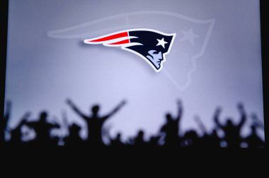 New England Patriots. Taraftarlar Amerikan Ulusal Foorbol Ligi 'nin profesyonel takımını destekliyor. Taraftarların silueti ön planda. Büyük ekranda logo.
