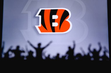 Cincinnati Bengalleri. Taraftarlar Amerikan Ulusal Foorbol Ligi 'nin profesyonel takımını destekliyor. Taraftarların silueti ön planda. Büyük ekranda logo.