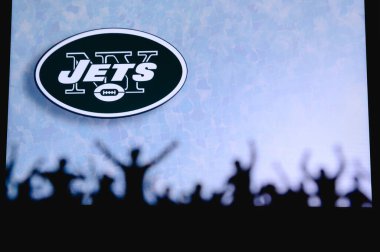 New York Jetleri. Taraftarlar Amerikan Ulusal Foorbol Ligi 'nin profesyonel takımını destekliyor. Taraftarların silueti ön planda. Büyük ekranda logo.