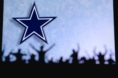 Dallas Kovboyları. Taraftarlar Amerikan Ulusal Foorbol Ligi 'nin profesyonel takımını destekliyor. Taraftarların silueti ön planda. Büyük ekranda logo.