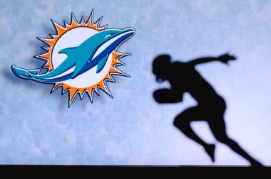 Miami Yunusları. Profesyonel Amerikan futbolcusunun silueti. Arka planda NFL kulübünün logosu, boşluğu düzenle.