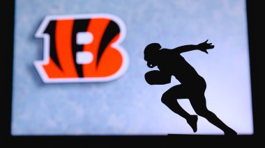 Cincinnati Bengalleri. Profesyonel Amerikan futbolcusunun silueti. Arka planda NFL kulübünün logosu, boşluğu düzenle.