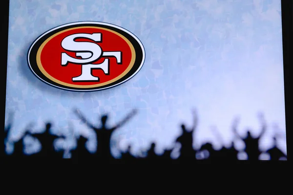 サンフランシスコ49Ers ファンはアメリカン ナショナル フットボール リーグのプロチームをサポートしている 前景の支持者のシルエット 大きな画面上のロゴ — ストック写真