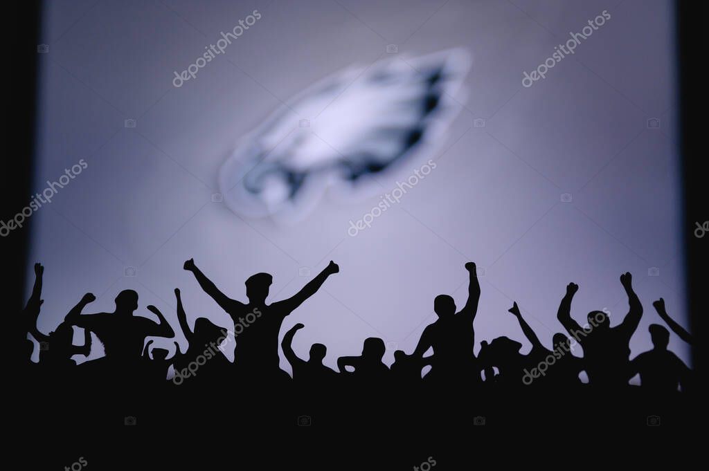 Philadelphia Eagles. Fans support professional team of American National Foorball League. Silhouette of supporters in foreground. Logo on the big screen.