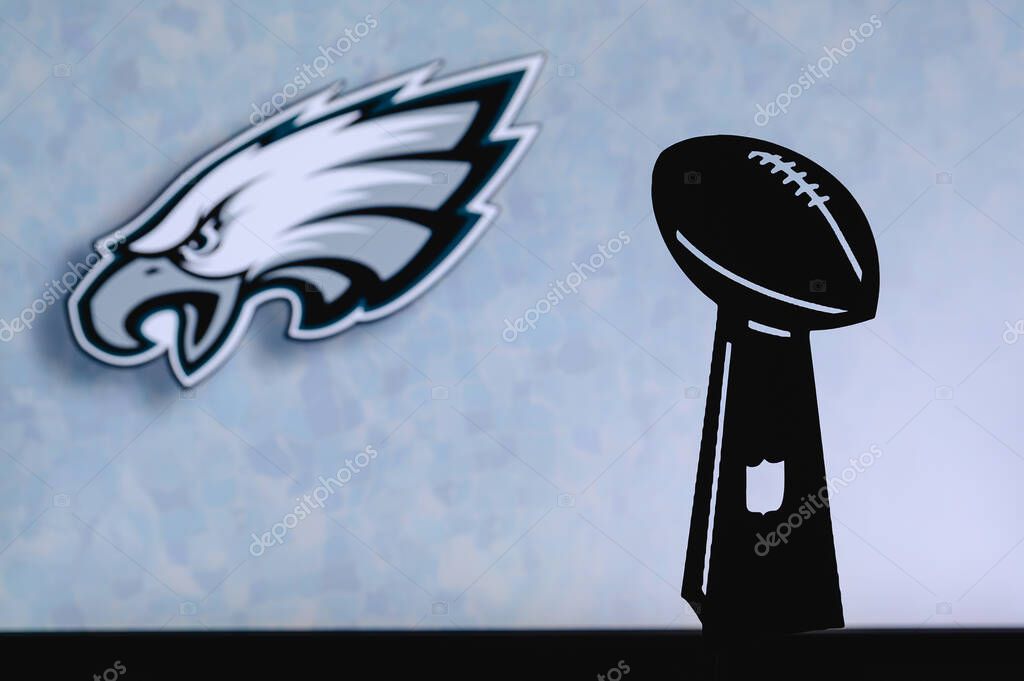Philadelphia Eagles professional american football club, silhouette of NFL trophy, logo of the club in background.