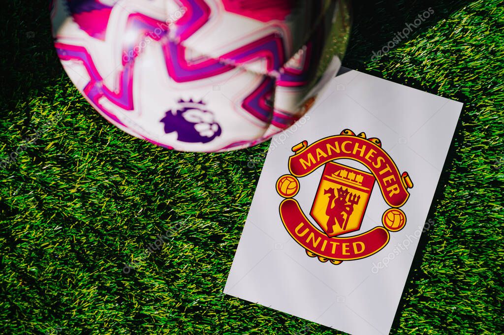 VIENNA, AUSTRIA, MAY 26, 2025: Manchester United logo of football club of Premier League. Official ball for season 2025 and 2026. And logo of soccer club in major British league on green grass