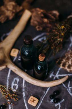 Sihirli iksir şişesi. İksirler, bitkiler ve okült ekipmanlarla modern cadılık konsepti. Karanlık bir arkaplanda kopyalama alanı olan büyülü bir yaşam.