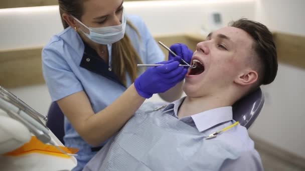 Dentystka Ortodonta Bada Zęby Młodego Mężczyzny Pomocą Igły Lustra Higiena — Wideo stockowe