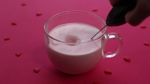 ピンクの背景に大きなガラスカップにピンクの月のミルクを作るためのミルクの泡を使用してください — ストック動画