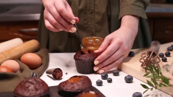 Vrouwelijke Handen Gieten Karamel Vulling Chocolade Cupcake Een Vrouw Maakt — Stockvideo