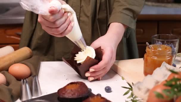 クリームと新鮮なブルーベリーでチョコレートカップケーキを飾る クッキングバッグ お菓子作りカップケーキパーティー おいしいカップケーキにクリームを絞る — ストック動画