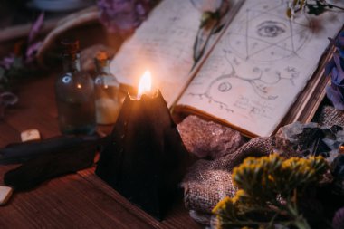 Büyü, mühür, siyah mum ve cadı masasında bitkiler olan eski bir kitabı aç. Esrarengiz, esrarengiz, kehanet ve cadı kavramı. Cadılar Bayramı klasik arka planı