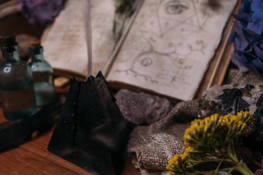Büyü, mühür, siyah mum ve cadı masasında bitkiler olan eski bir kitabı aç. Esrarengiz, esrarengiz, kehanet ve cadı kavramı. Cadılar Bayramı klasik arka planı
