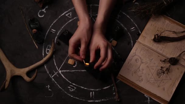 女性魔女占い師の女の子のトップビューは 五角形の背景に魔法の黒いろうそくを点灯します — ストック動画