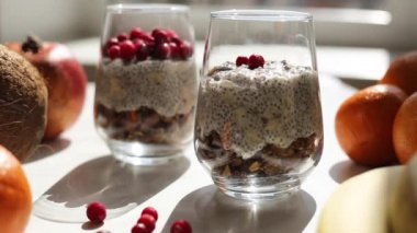 Hindistancevizi sütüyle chia tohumlarından puding yapma süreci. Cama chia tohumu yerleştirme işlemi. Sağlıklı vejetaryen yemeği. Mutfakta pencereden gelen güneş ışığı..