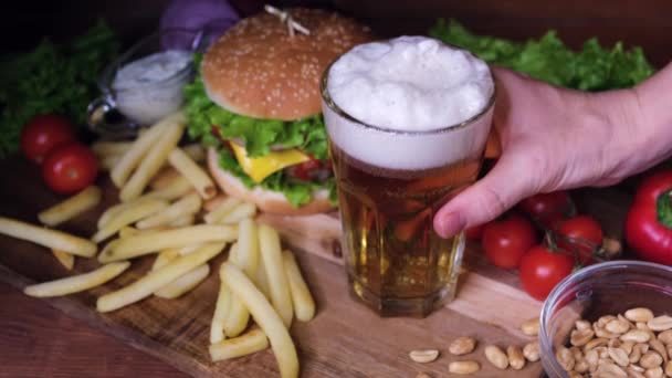 Uma Mesa Madeira Com Cerveja Hambúrguer Batatas Fritas Mão Levanta — Vídeo de Stock