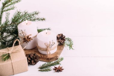 Noel mumları, hediye ve köknar dalları beyaz ahşap arka planda ışıklarla. Kopyalama alanı olan tebrik kartı