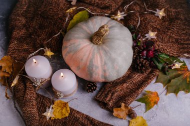Sonbahar kompozisyonu. Mumlu balkabağı, örgü süveter, çelenk ve kuru yapraklar. Sonbahar, sonbahar, Cadılar Bayramı konsepti. Beyaz kırsal arkaplan