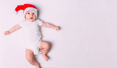 Yumuşak kumaş üzerinde Noel Baba şapkalı şirin bir bebek. İlk Noel 'de bebek. Noel Baba bebek. Yeni yıl tatili.