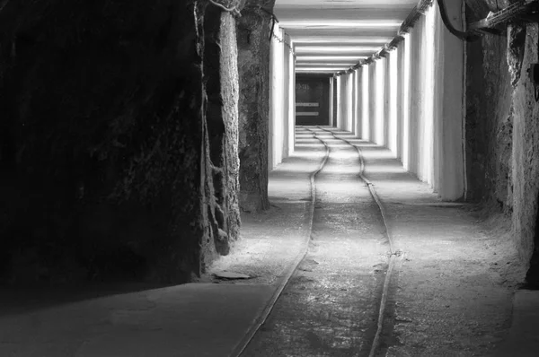 Un tunnel cavo nella roccia, un passaggio sotterraneo illuminato . — Foto Stock