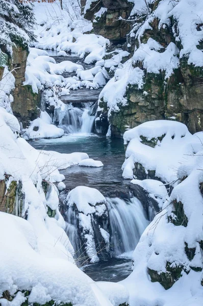 Winterlandschap met een waterval tussen de rotsen. — Stockfoto