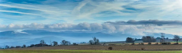 Panorama, nuvens penduradas sobre uma cordilheira . — Fotografia de Stock