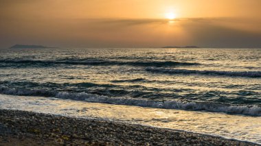Deniz üzerinde Korfu Sunset, arka planda su üzerinde turuncu bir güneş ile bir ada.