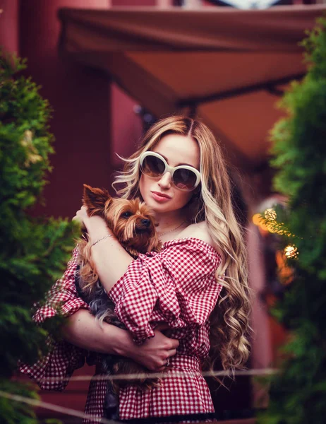 portrait of a stylish woman hugging a dog in the city