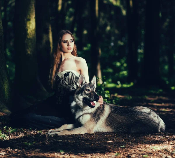 Fashion photo of a stylish woman with a dog in forest
