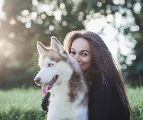 woman hugs siberian husky dog in park