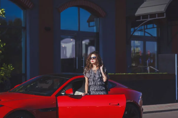 woman near a red car in the city
