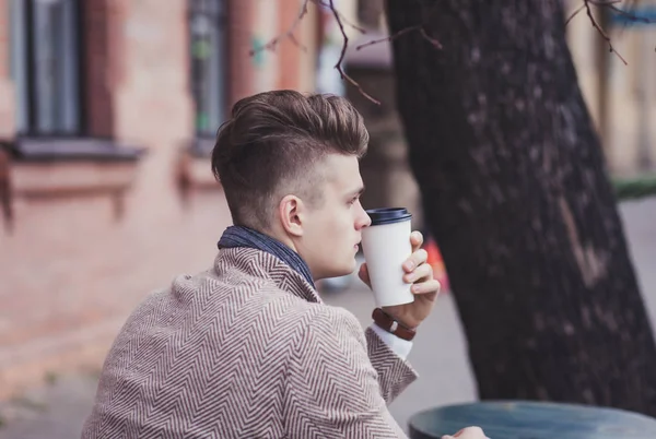 lonely man holds a coffee to go