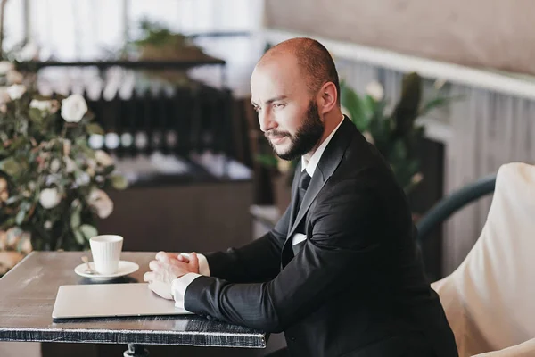 business man in an expensive suit and watch sit in a cafe waiting for a meeting